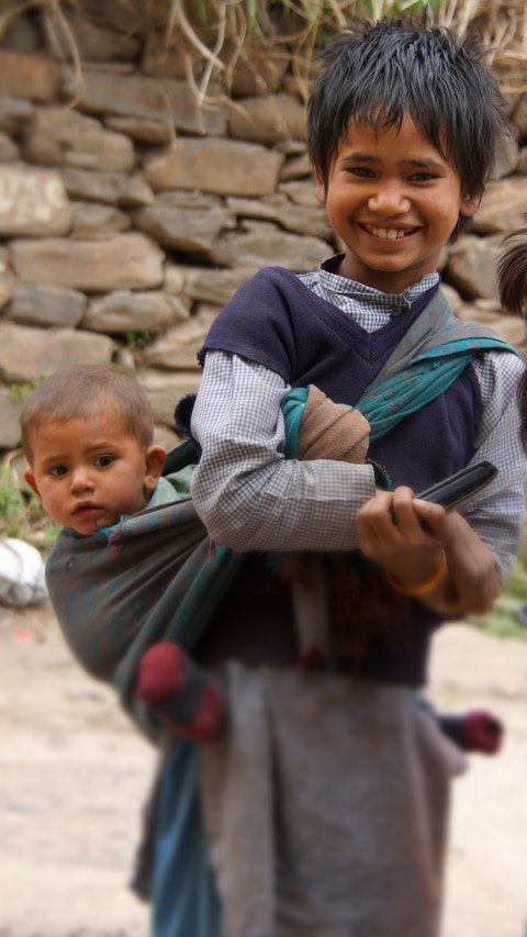 portrait de fillette très souriante portant un bébé sur son dos à Rohru