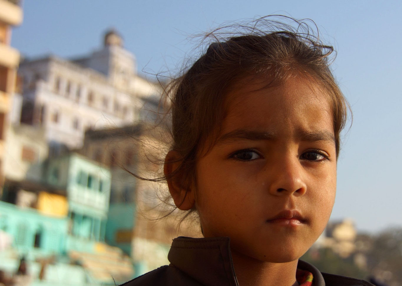 Une petite fille au regard sérieux et triste pose pour la photo - ghat - Varanasi
