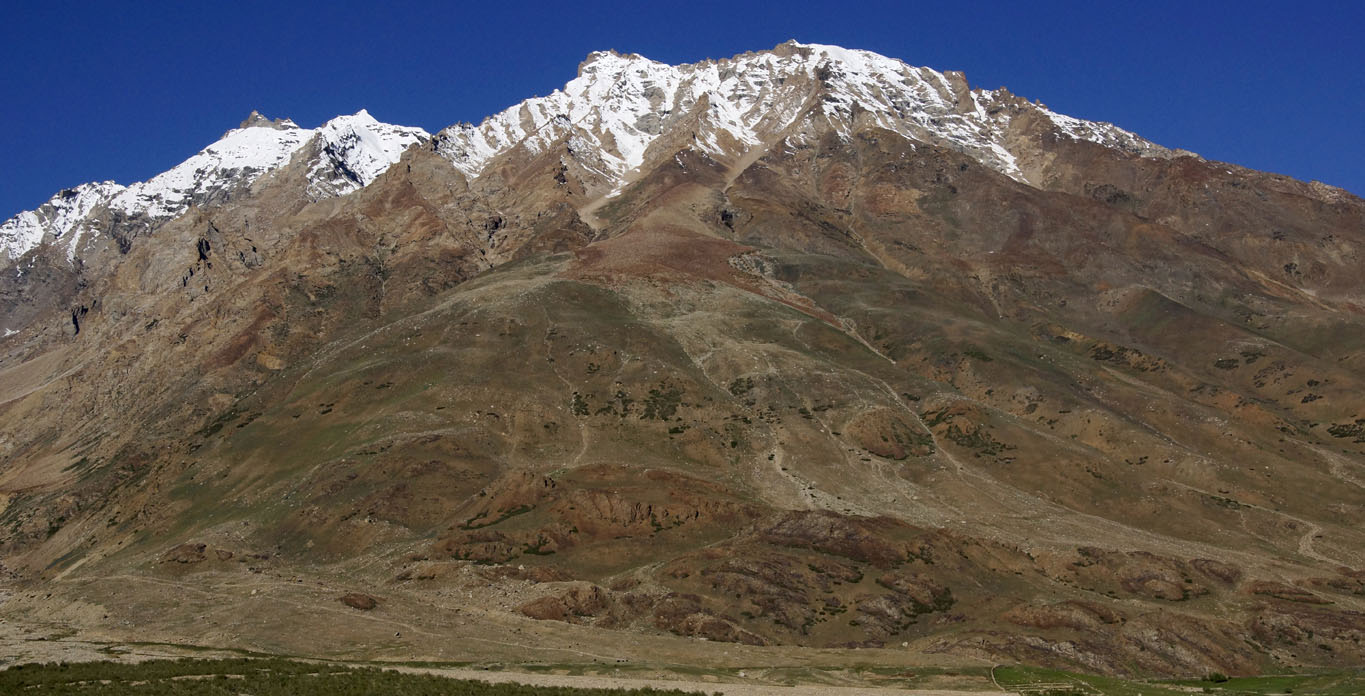 Tout au sommet du massif recouvert d'un tapis ocre et vert, une dentelle de neige au Zanskar