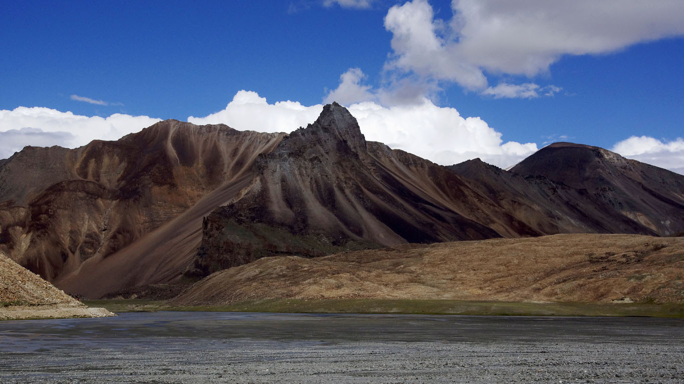Une magnifique montagne aux sommets escarpés aux couleurs allant du rouge brique au noir en passant par des bruns fauves surplombe la rivière entre Leh et Keylong