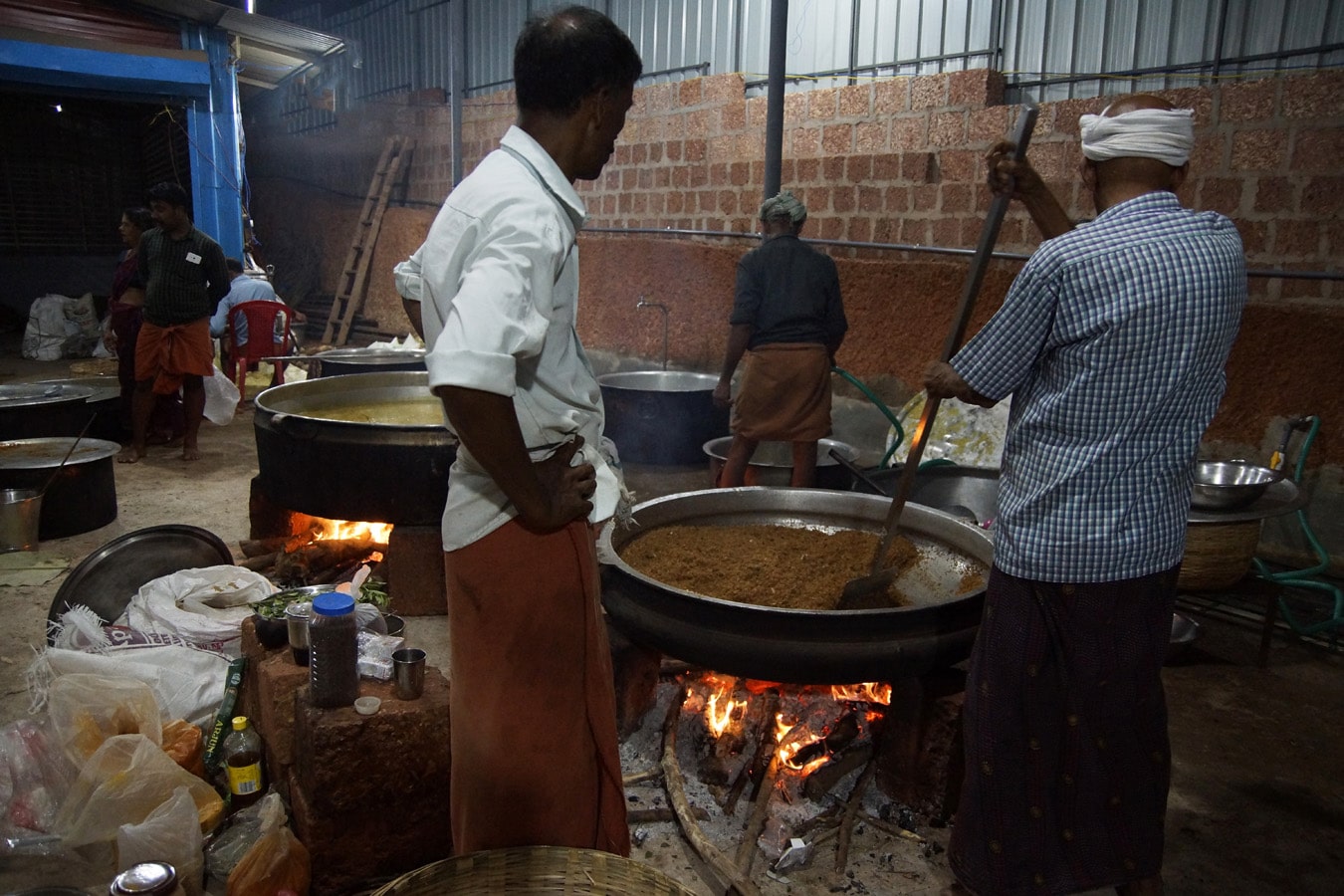 le feu flambe sous les immenses marmites pour la préparation du repas offert lors d'un rituel de theyyam à Kannur côte Malabar
